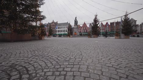 an early morning bicyclist pedals across a mostly deserted bruges christmas market square