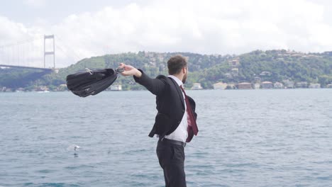 happy and successful businessman. he rejoices by the sea in the city.