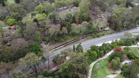 drone volando sobre un hermoso jardín botánico con estanque y sendero hacia un cementerio cerca de