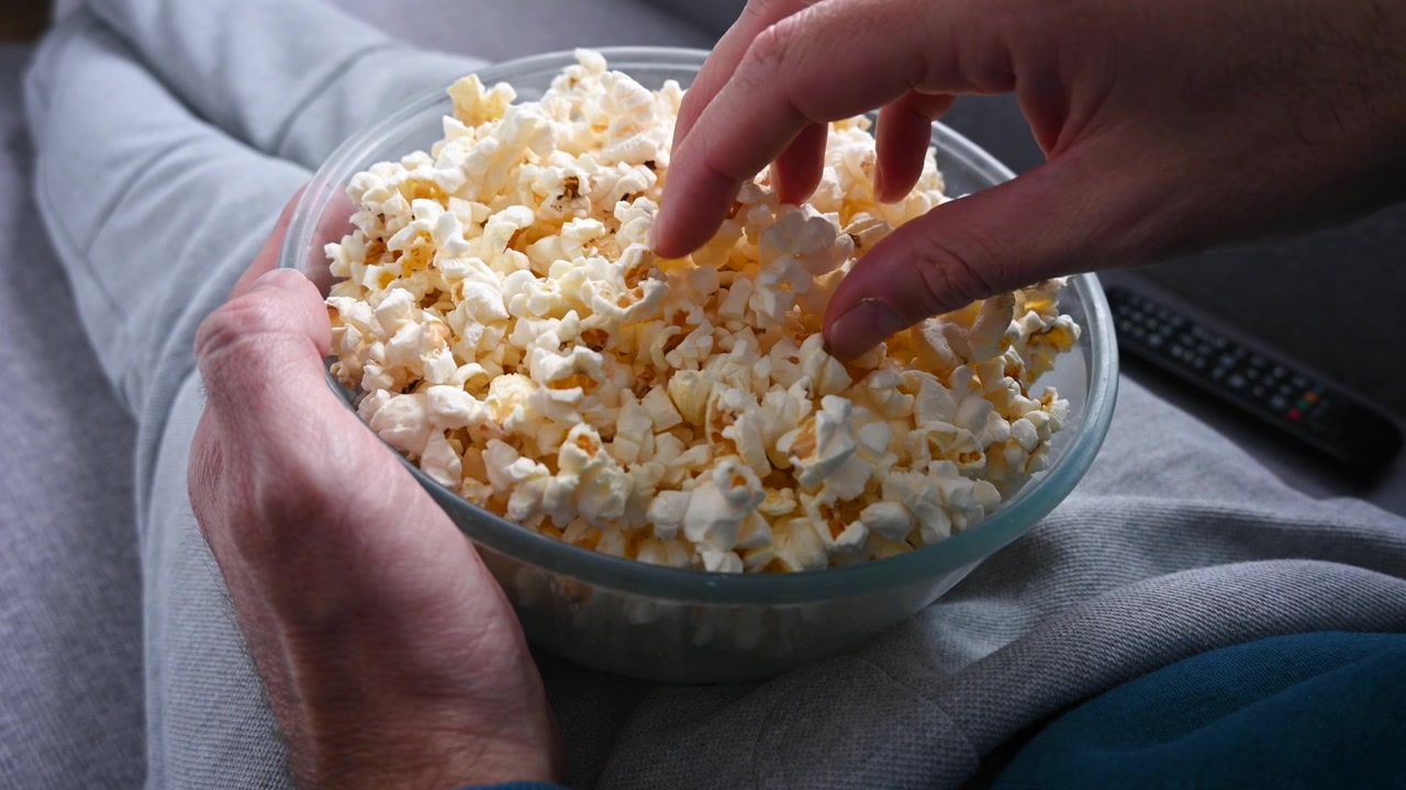 Uomo che mangia popcorn sul divano