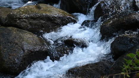 Snowmelt-stream-running-over-river-rocks-on-a-hike,-close-up