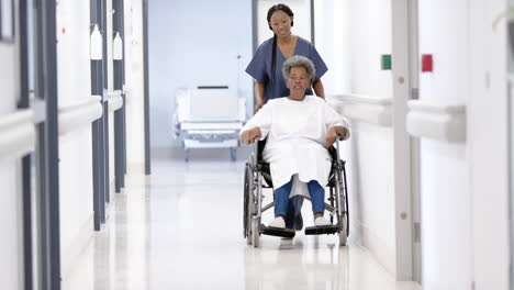 médica afroamericana caminando con una mujer anciana en silla de ruedas en el hospital, en cámara lenta