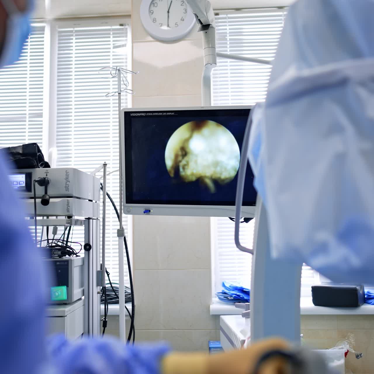 Unrecognized surgeon stands operating the patient. Doctor watches the operation on the screen