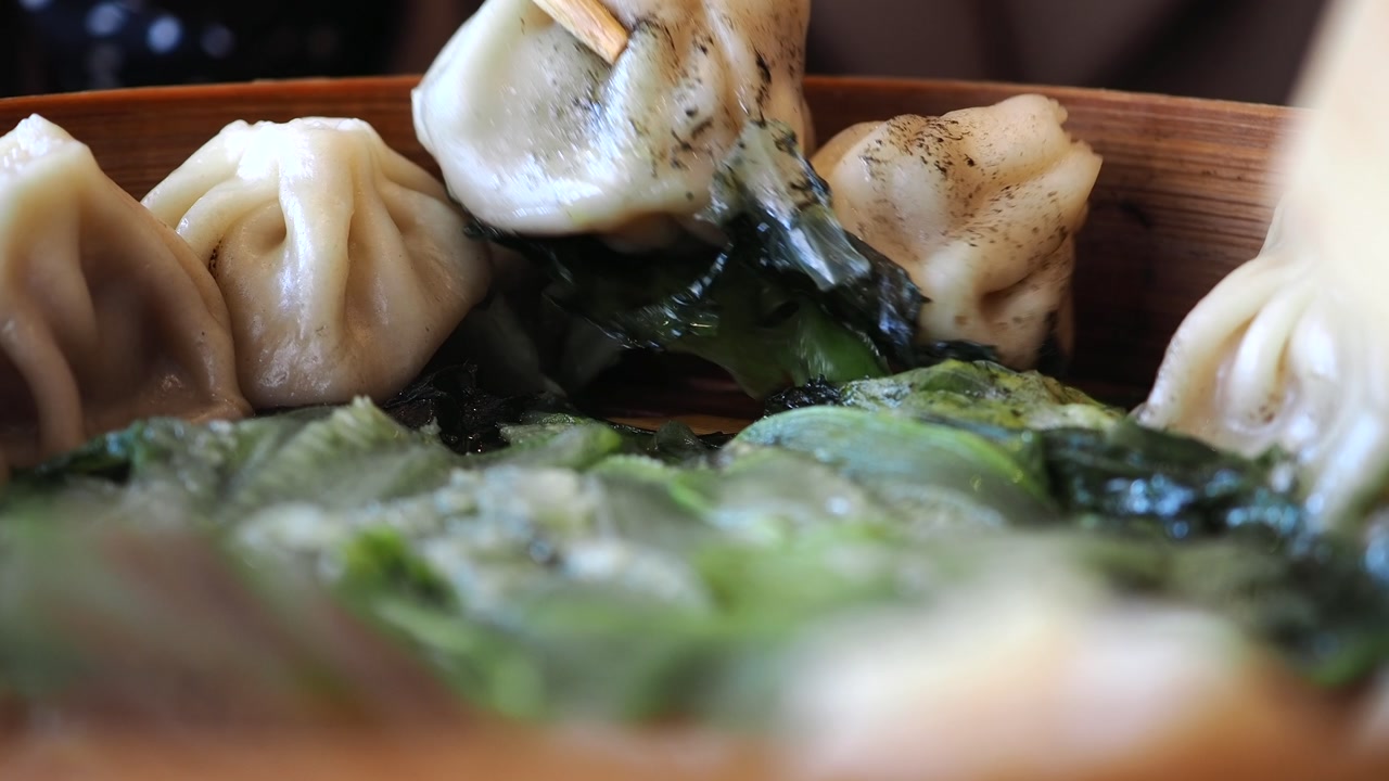 Steamed Xiao Long Bao Dumpling Lifted with Chopsticks from Bamboo Steamer