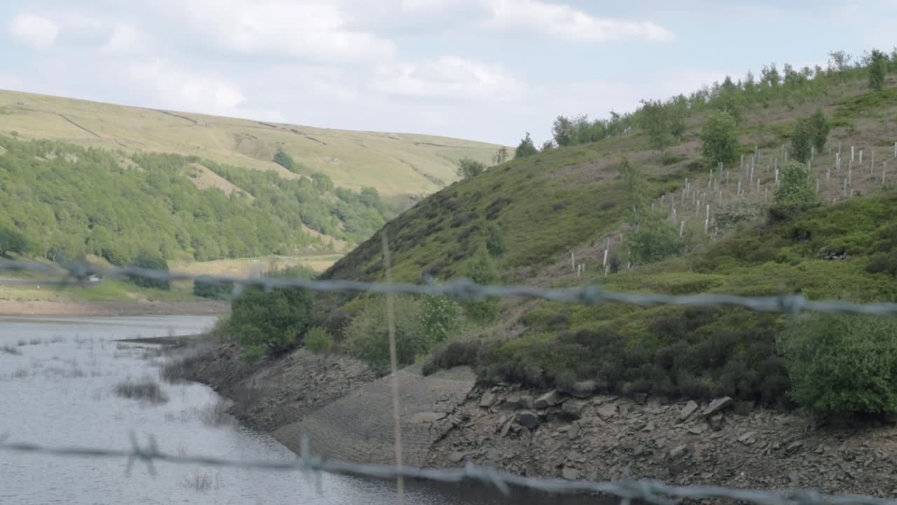 Nádrž Butterley a kopce Yorkshire, široký naklápěcí záběr přes plot.