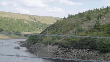 Butterley-reservoir-and-Yorkshire-hills-wide-tilting-shot-through-fence