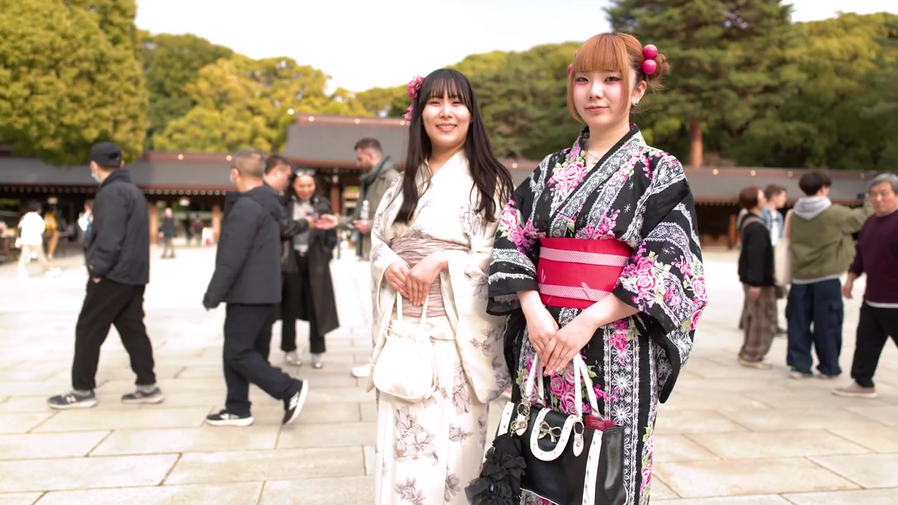Deux femmes vêtues de kimonos traditionnels se tiennent dans une cour ensoleillée d'un sanctuaire japonais.
