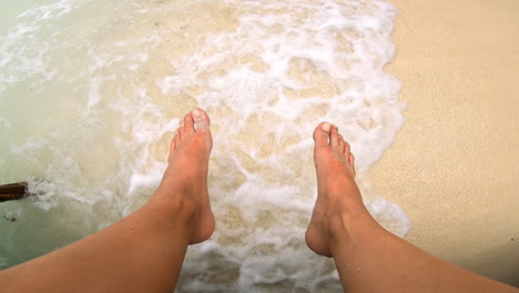 feet in the shallow ocean waves on a beach