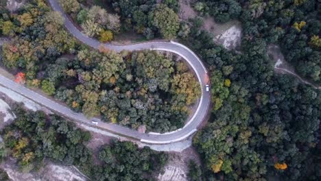 Top-down-aerial-shot-of-a-hairpin-bend-on-a-European-mountain-road-with-cars-driving