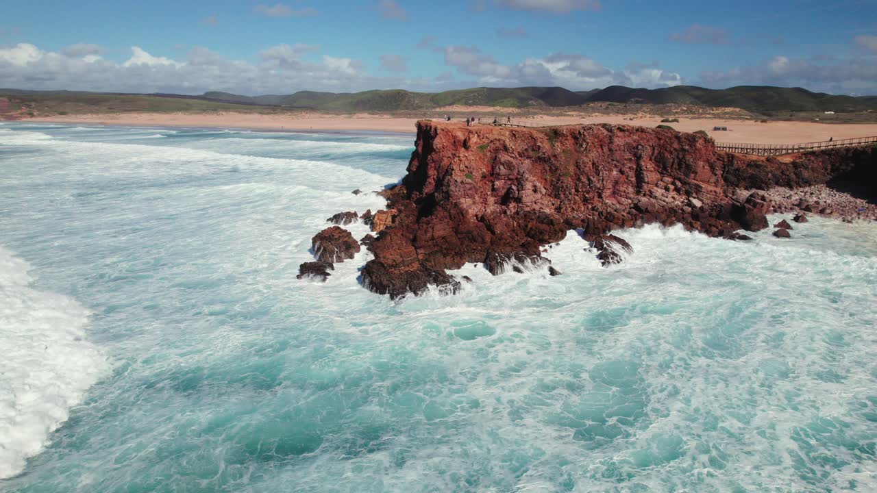 Push in panoramic view of peninsula with waves crashing and beach shoreline in Bordeira, the algarve region of Portugal by 4k drone