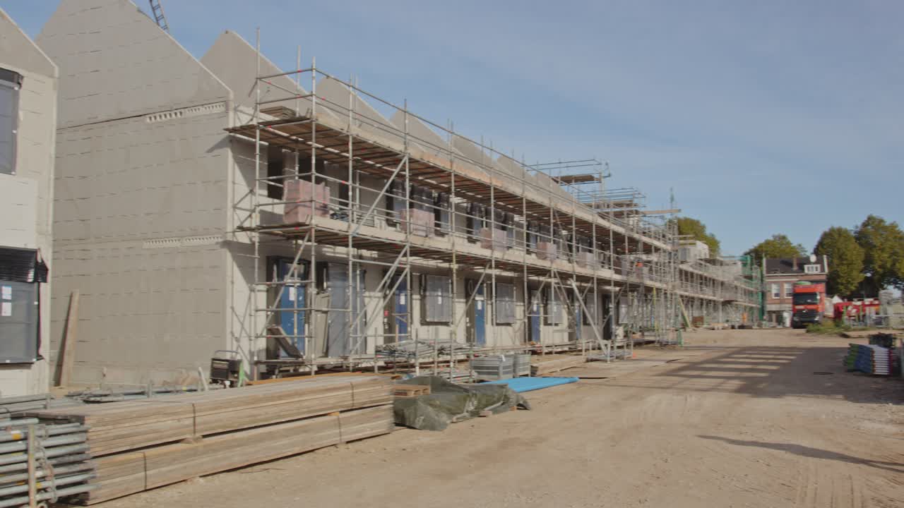 Pan of a long row of houses under construction in a newly built suburban neighborhood on a sunny day