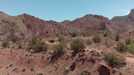 Dynamic-aerial-tracks-dusty-trucks-on-arid-canyon-land-desert-road