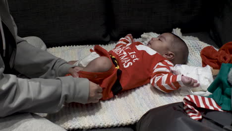 lindo bebé de 3 meses vestidos de rojo mi primer traje de navidad puesto sobre una manta obteniendo un cambio de pañal