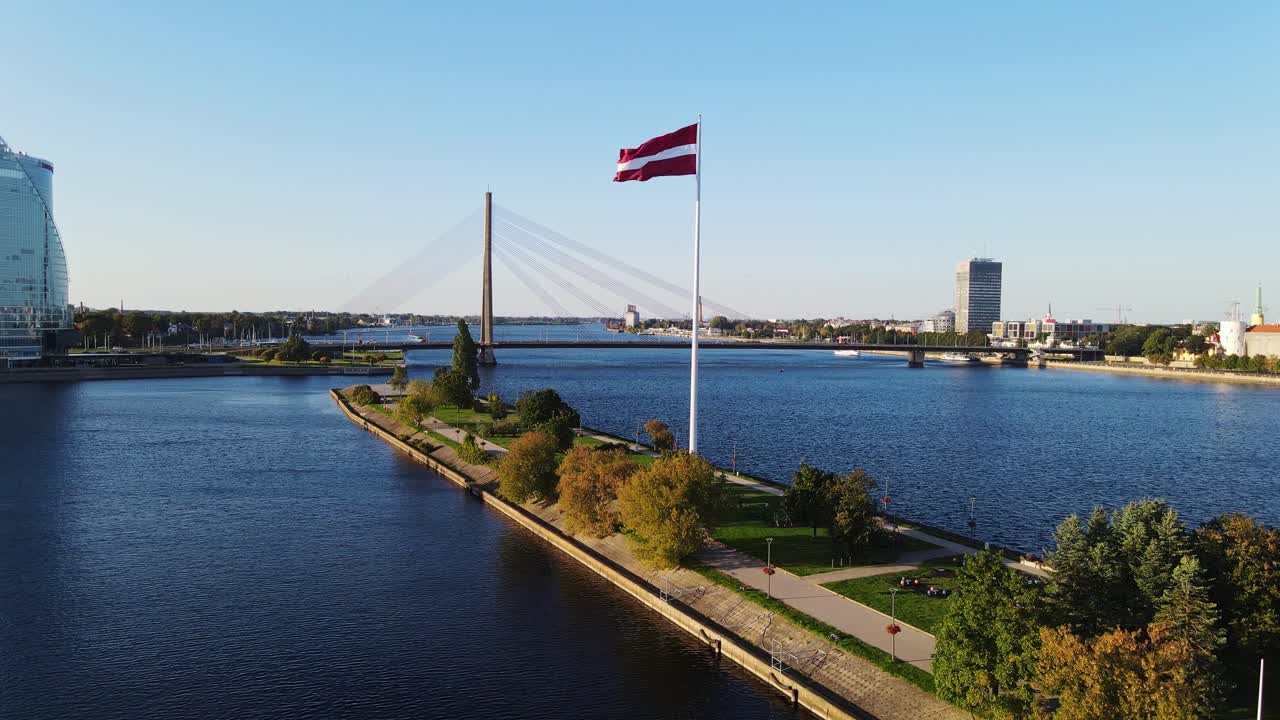 La ripresa aerea mostra la bandiera lettone, le acque calme e il moderno paesaggio urbano di Riga
