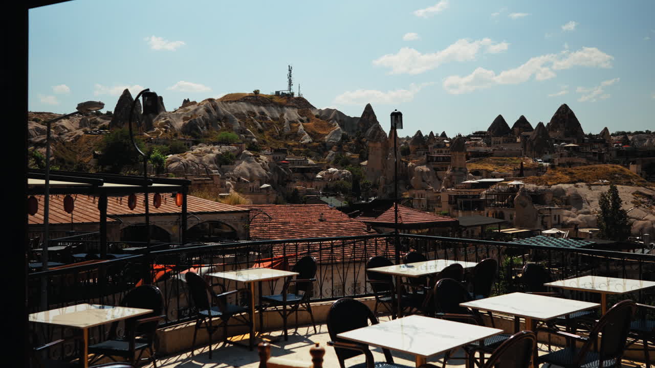 Cozy restaurant terrace in Göreme with panoramic view of Cappadocia’s iconic rock formations and traditional architecture under clear skies. Authentic Turkish travel atmosphere.
