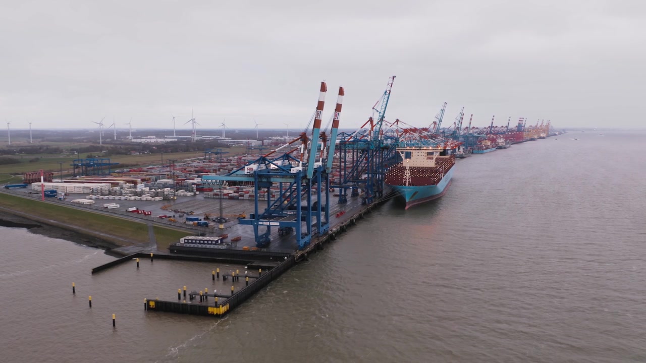 Aerial panoramic view over the North Sea Terminal of the Bremerhaven port with big Container Ship being loaded by crane in the background.