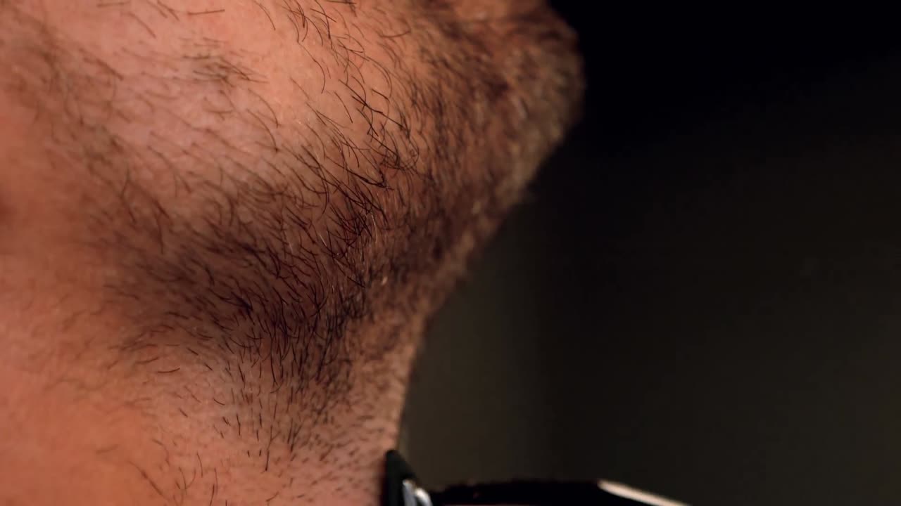 primer plano de un hombre afeitando con una maquinilla de afeitar eléctrica