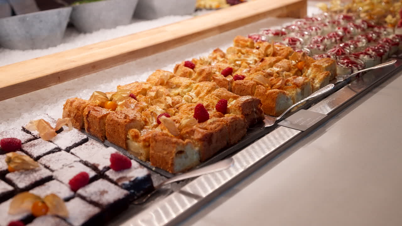 Pastry buffet display with assorted baked goods arranged on trays in indoor setting