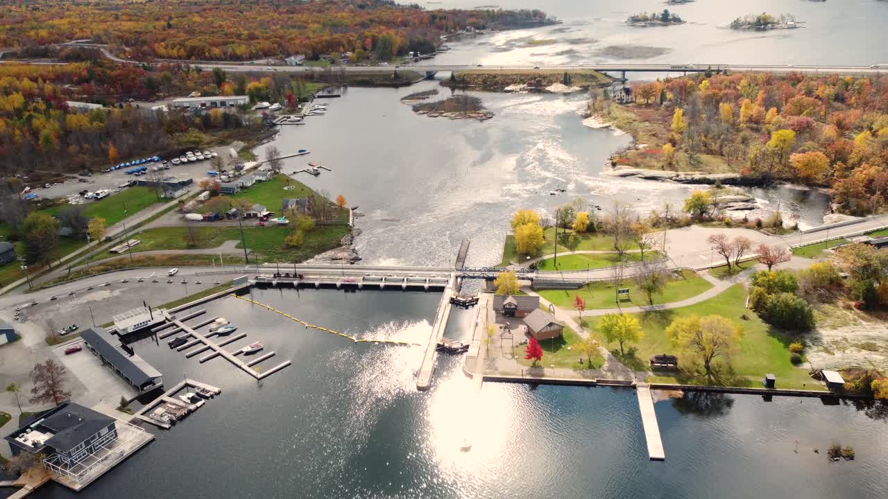 강 옆에 있는 마을 항구의 공중 풍경 전망, 노란색 빨간색과 주황색 단풍이 있는 다채로운 가을 나무로 둘러싸여 있습니다.