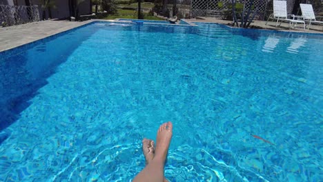 Piernas-De-Mujer-Chapoteando-En-Una-Piscina-Azul