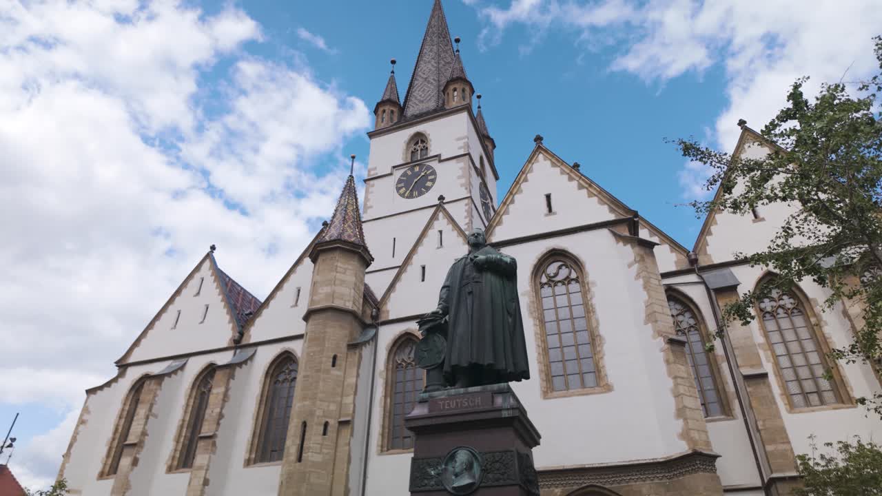 Scenic view of the Lutheran Cathedral of Saint Mary in Sibiu, featuring the statue of Bishop Georg Daniel Teutsch in the foreground