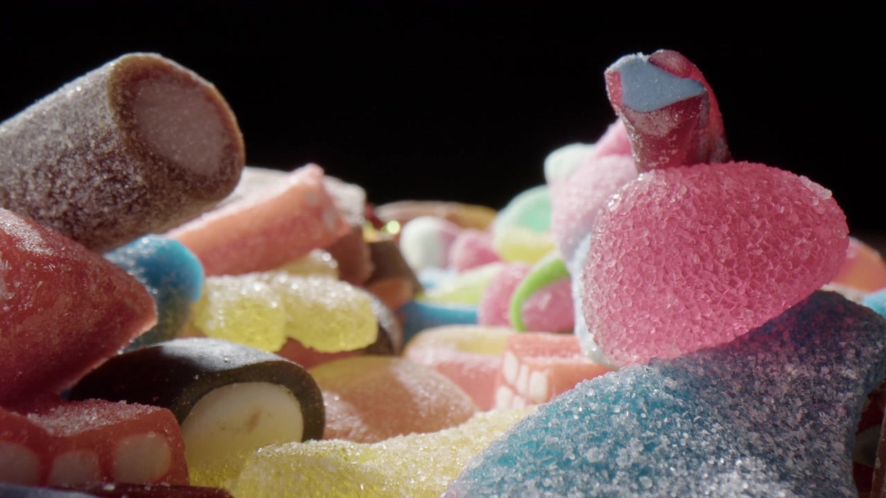 Ripresa con slider a sonda su un assortimento di caramelle zuccherate e colorate, concetto di golosità.