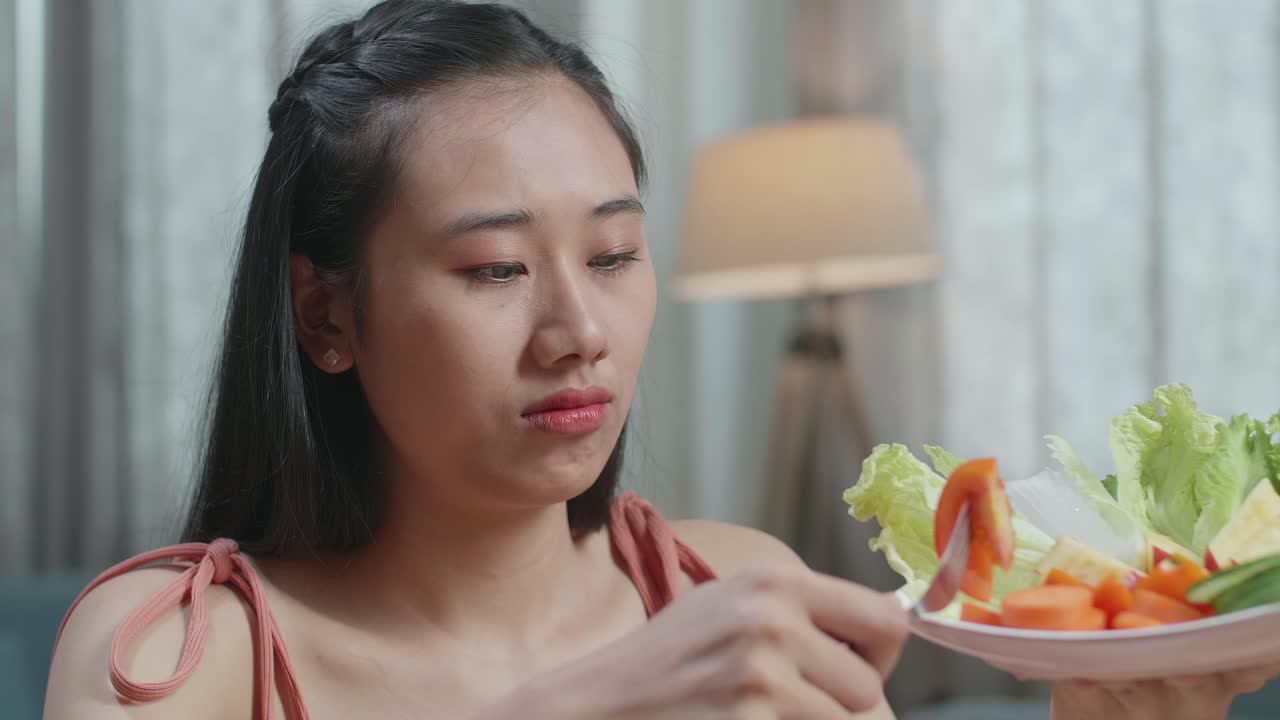 집에서 식사를 하는 동안 건강한 음식을 먹는 것을 싫어하기 때문에 머리를 흔들고 있는 아시아 여성의 근접 사진