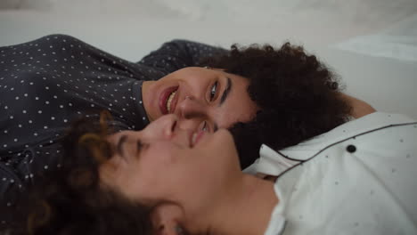 una pareja feliz hablando en la cama.