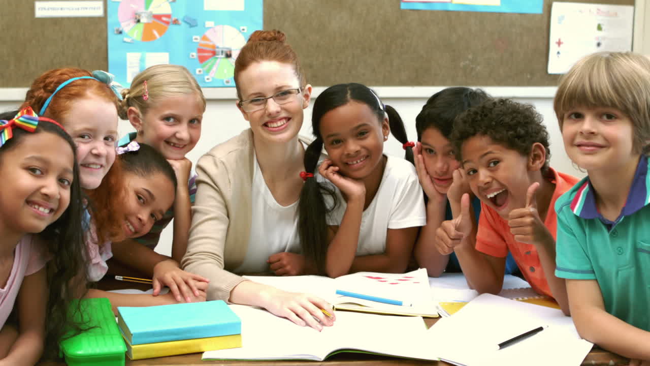 Teacher and pupils smiling at camera in classroom