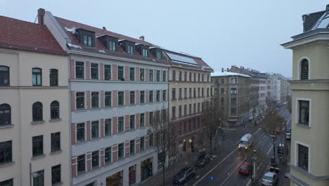 Blick-Auf-Die-Stadt-Mit-Schneefall-In-Der-Dämmerung-In-Zeitlupe,-Stadtgebiet-Mit-Winterwetter-Und-Vorbeifahrenden-Autos-Auf-Der-Straße-Von-Leipzig,-Deutschland