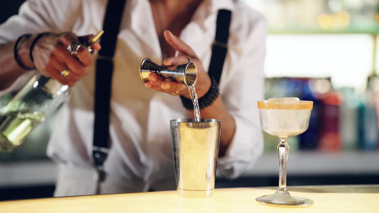 Professionel bartender hælder væske i cocktailshaker