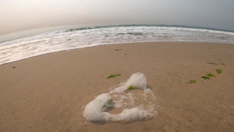 Sea-foam-being-blown-away-by-ocean-breeze-in-Monterey-Bay,-California