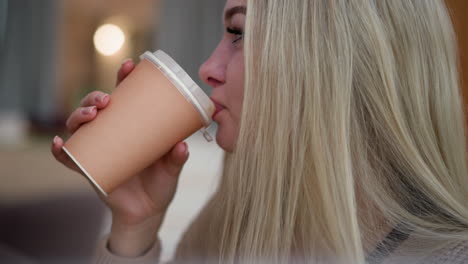 close-up side view of elegant lady sipping coffee with focus, starring thoughtfully at something, soft bokeh lights in background creating a serene atmosphere in the cafe