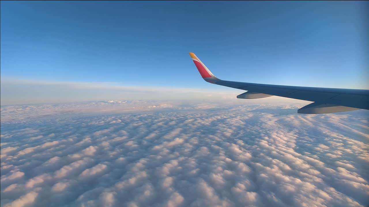Timelapse: vista dal finestrino dell'aereo, ala che vola sopra un mare di nuvole in un pomeriggio soleggiato.