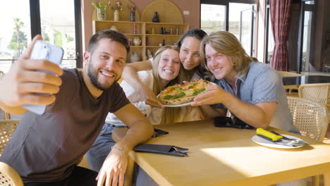 grupo de amigos tomando una foto selfie y divirtiéndose mientras comen pizza en un restaurante 1
