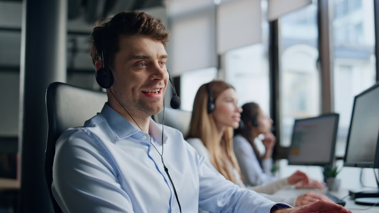 Smilende mann jobber i et telemarketingsenter. Vennlig mannlig leder konsulterer kunde.