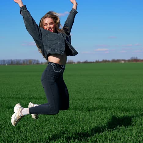 Happy girl in jeans on a green meadow. Beautiful young woman jumping joyfully on a field in a bright day. Cheerful model among nature