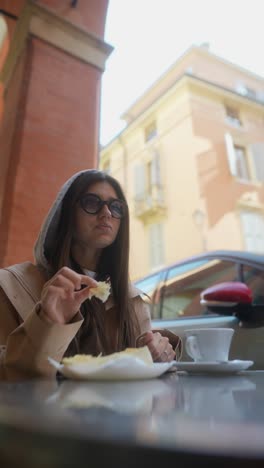 woman eating sandwich in outdoor cafe
