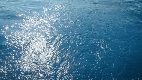 sunlight reflection in the blue sea - view from a sailing boat - high angle shot