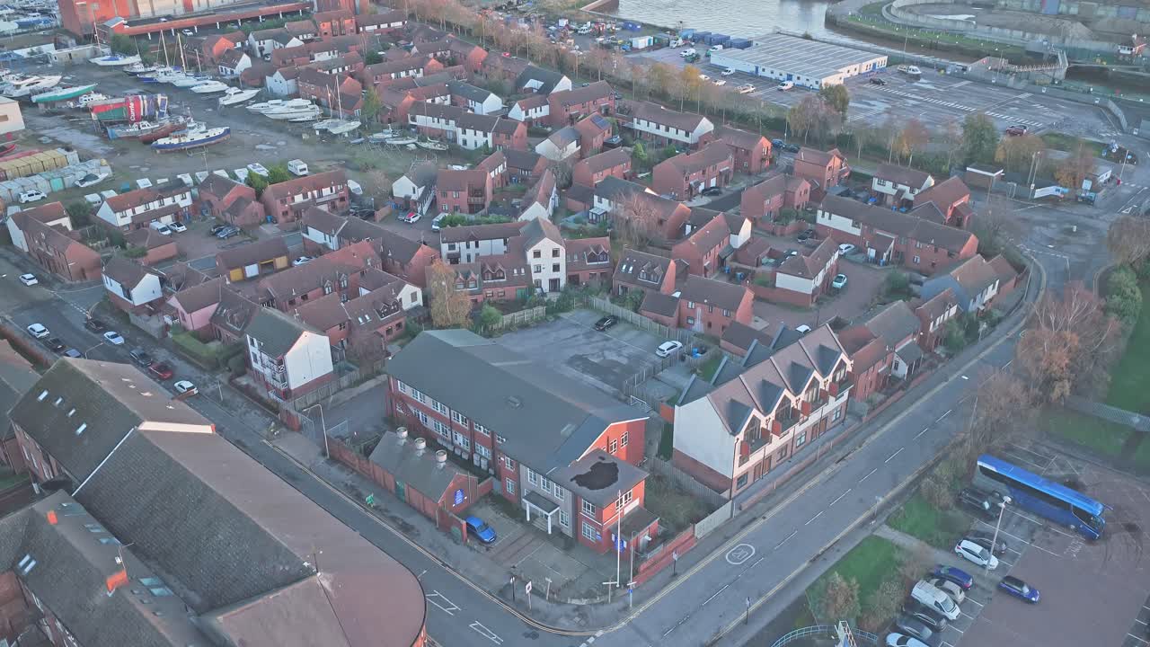 Drone shot at dusk over compact estate of red‑brick terraced and semi‑detached houses and low‑rise apartment blocks at Kingston Wharf, with Hull Marina’s boat moorings and waterside infrastructure
