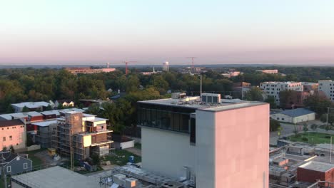 drone-shot-behind-a-building-in-a-small-city-with-trees-in-the-background