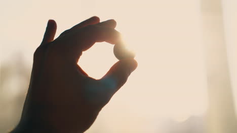 man-hand-with-little-coin-at-bright-sun-backlight-close-view