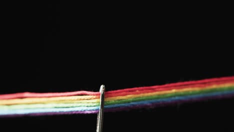 Video-of-micro-of-rainbow-coloured-threads-going-through-needle-with-copy-space-on-black-background