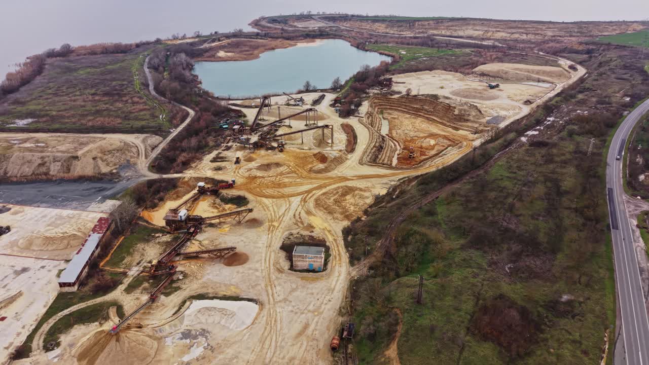Sand quarry and extraction site near water body during cloudy day