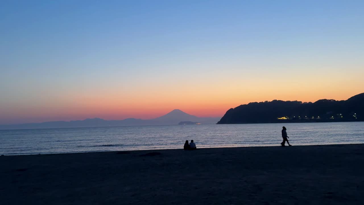 夕暮れのビーチの人々のシルエットと遠くの山,静かで静かな