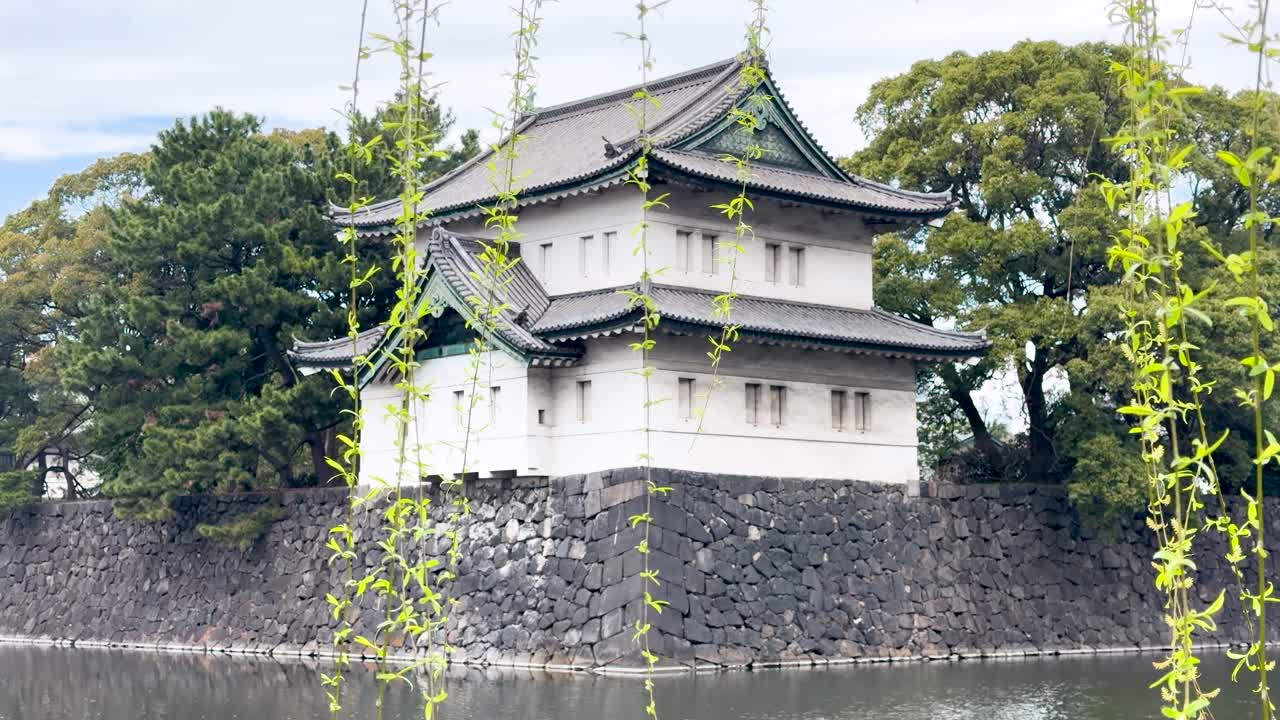 Inquadratura ampia statica di una tradizionale torre di guardia giapponese sopra un fossato in pietra a Tokyo
