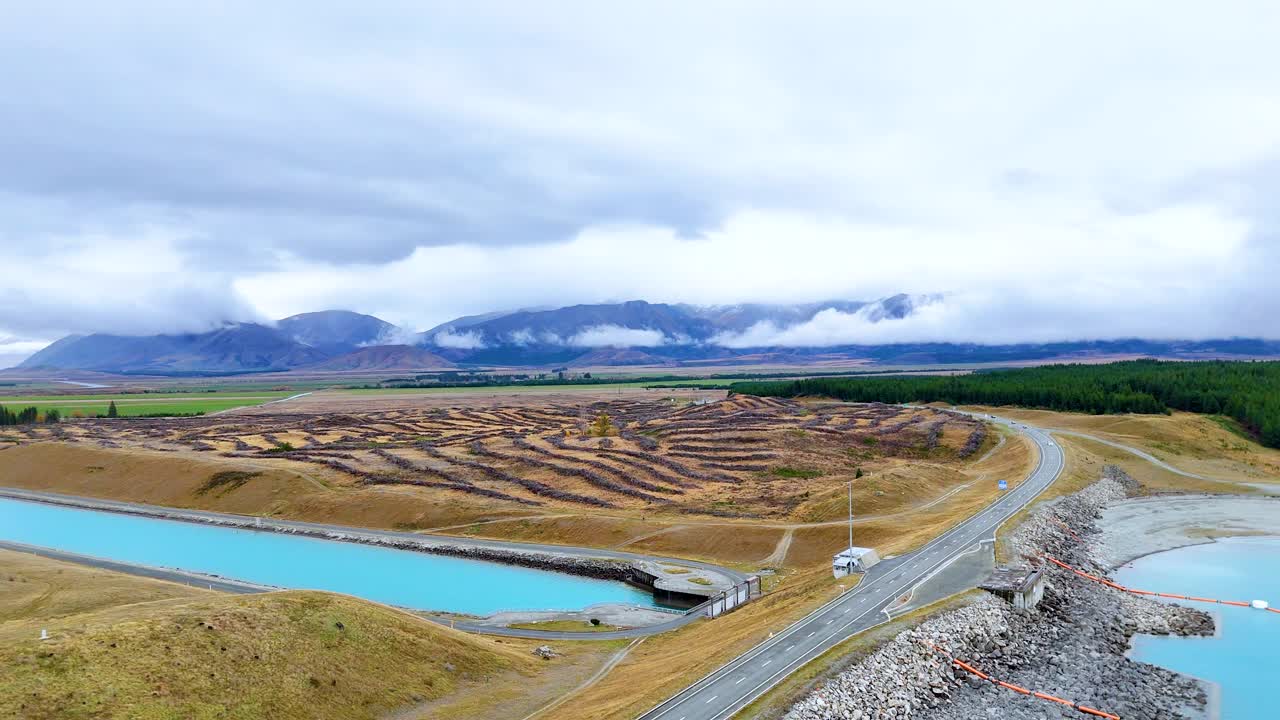 Aerial view of a winding road beside Lake Pukaki, capturing serene landscapes and cloudy skies in Canterbury, New Zealand