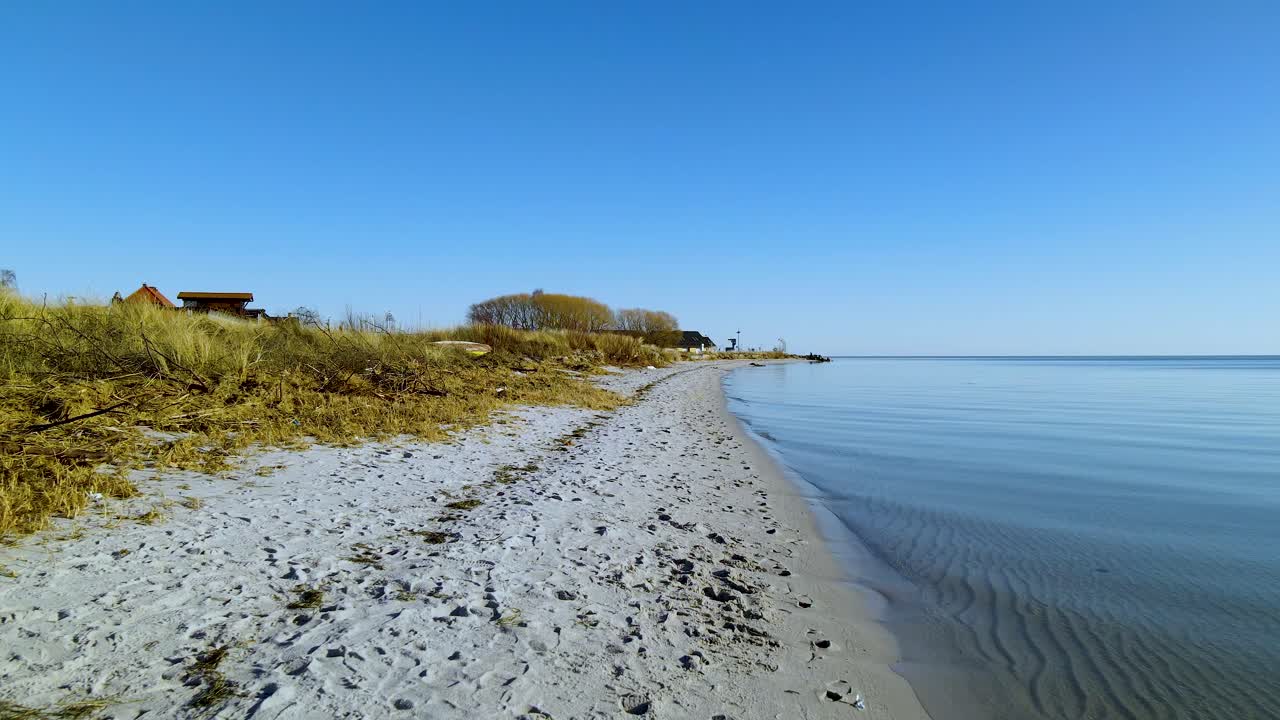 vista frontal de pov a lo largo de la costa de hel en polonia durante un clima hermoso con cielo azul claro - mar báltico tranquilo y plantas en crecimiento en la costa - lugar vacío y tranquilo