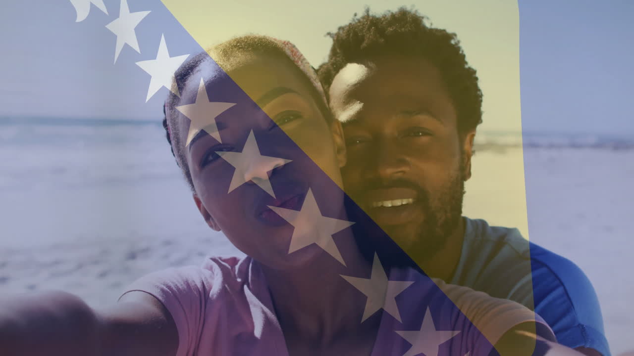una pareja tomando una selfie en la playa con la animación de la bandera de bosnia y herzegovina sobre ellos