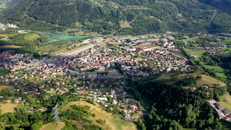 Flight-Over-Bourg-Saint-Maurice-Tarentaise-French-Alps-Summer-Day-Buildings-Railway-Station-Cloud-Shadow